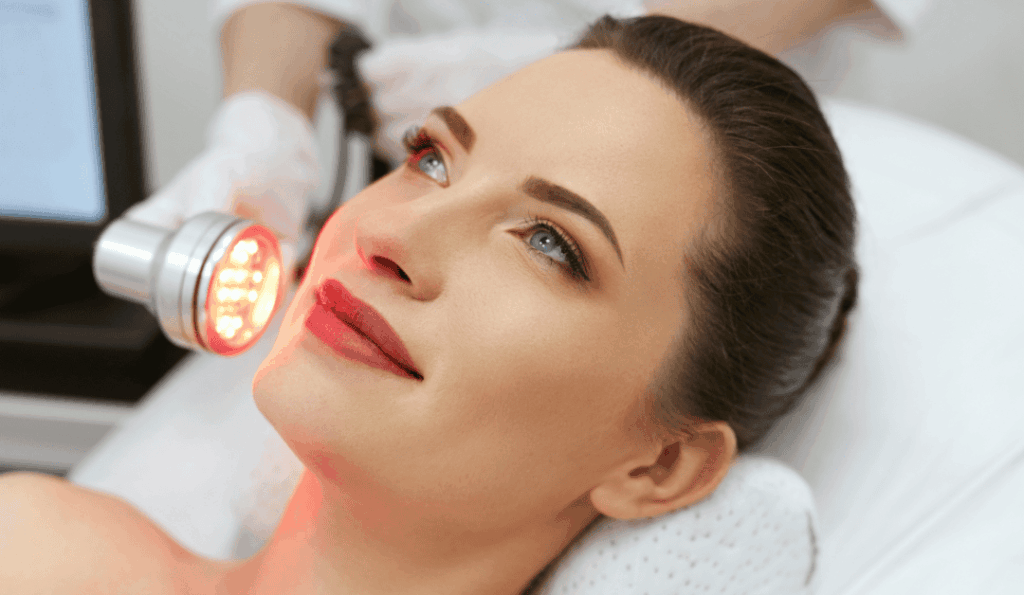 A woman receiving a targeted red light treatment on her face and neck.